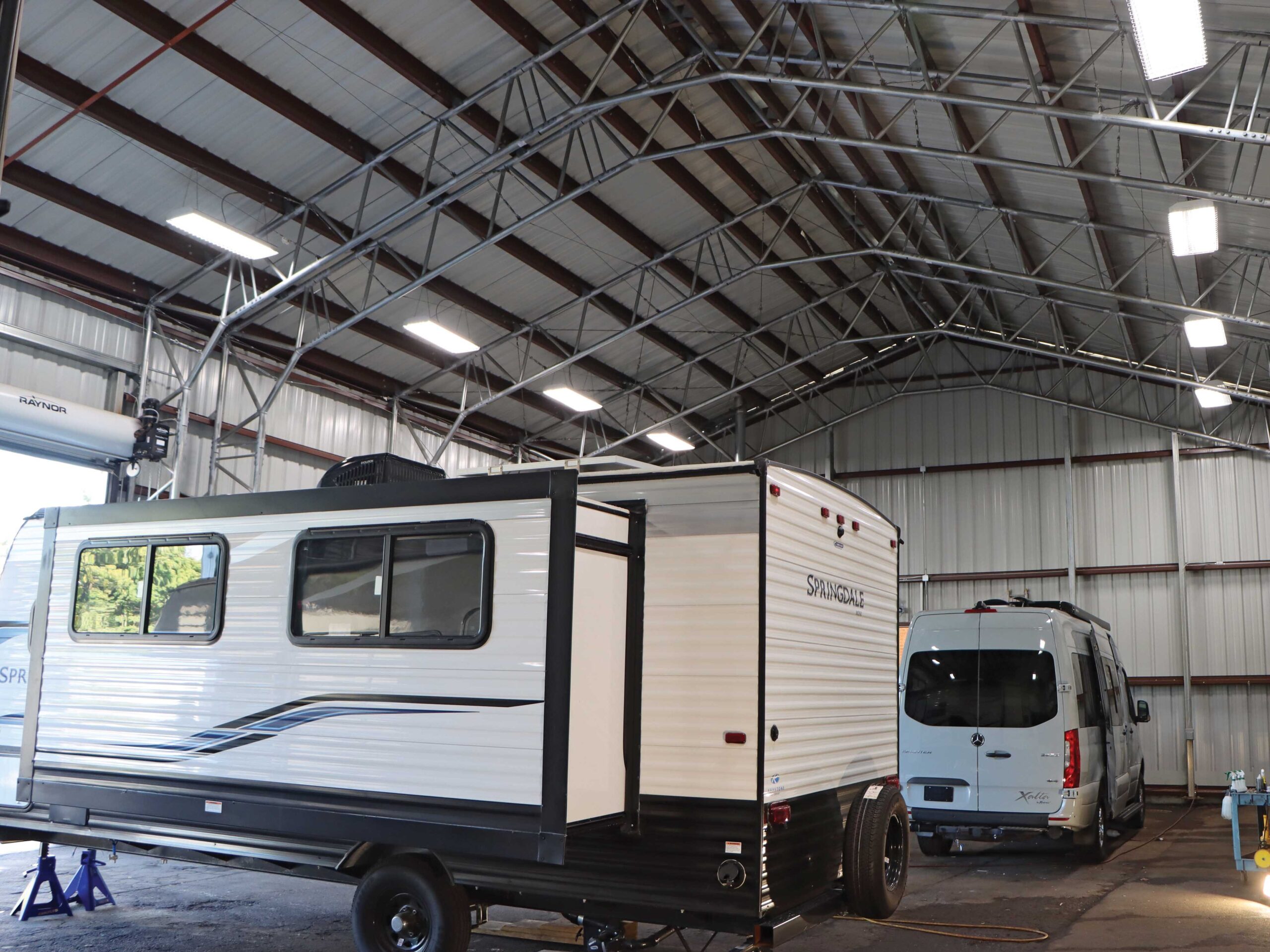 Interior of metal automotive building with a parked rv and van