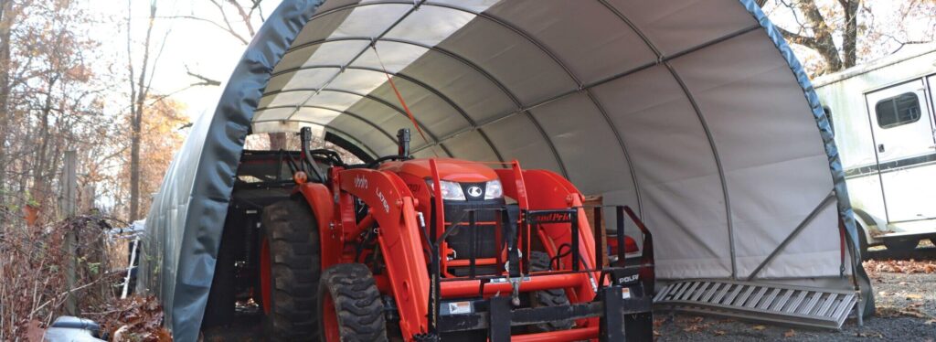 orange tractor being stored under portable garage tent